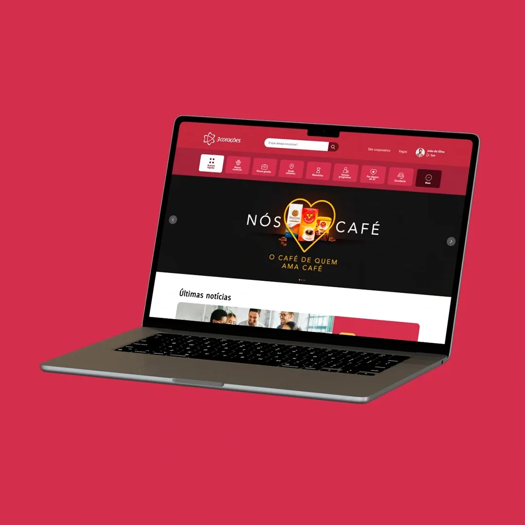 Notebook em perspectiva sobre fundo vermelho, com a home da intranet da 3corações aberta na campanha “Nós amamos café”