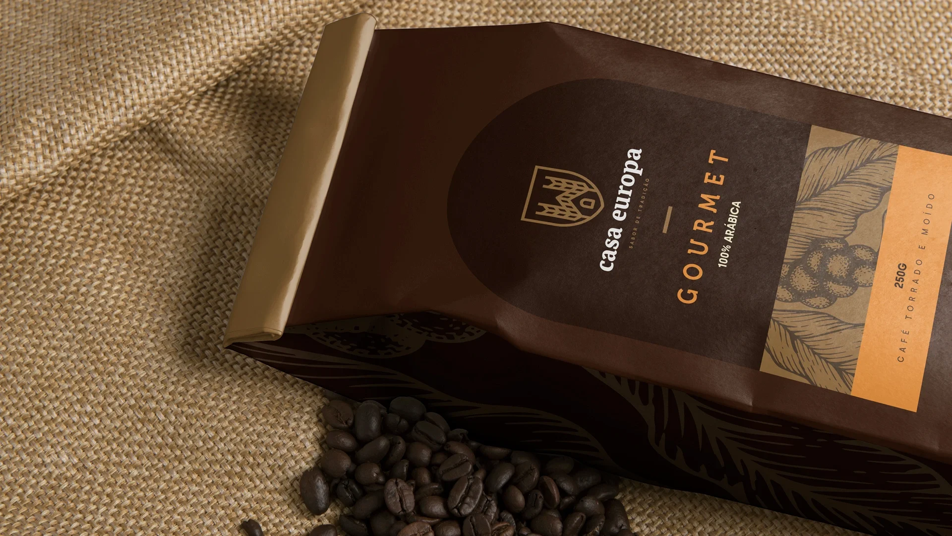 Embalagem de café Casa Europa Gourmet, 100% arábica, 250 g, em marrom e dourado com a ilustração do grão, apoiada sobre juta com grãos torrados ao lado.