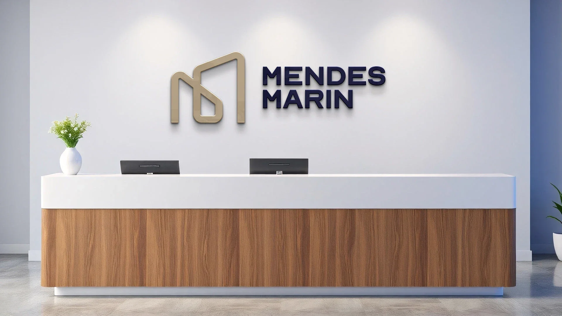 Recepção com o letreiro da Mendes Marin na parede: o monograma em dourado em relevo ao lado do nome em azul-noite, sobre um balcão de madeira e tampo branco.