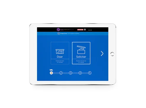 Tablet exibindo a plataforma projetoimpar.com, na escolha entre doar e solicitar um calçado.