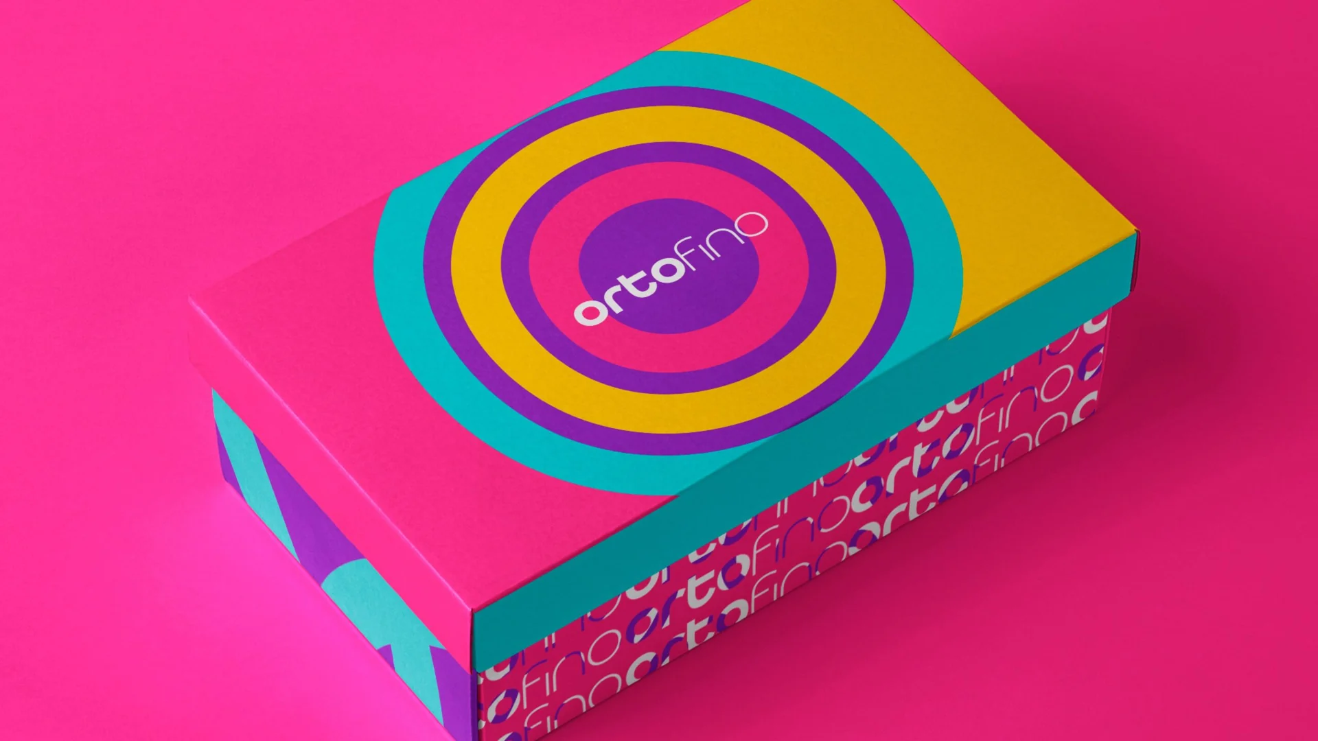 Caixa de calçado da Ortofino em rosa, turquesa e amarelo, com os círculos concêntricos da marca na tampa e o logotipo repetido na lateral, sobre fundo rosa.