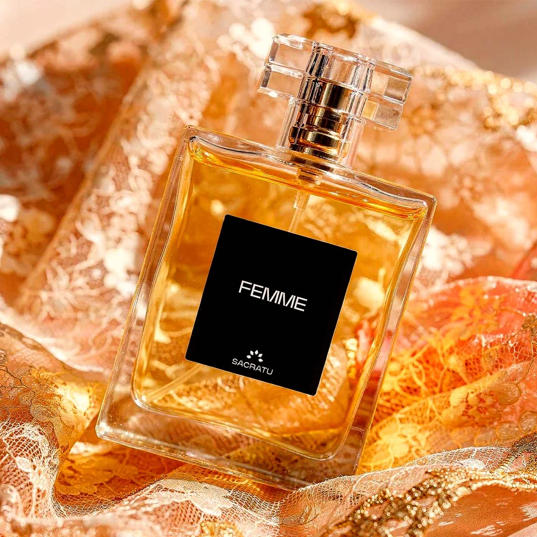 Frasco do perfume Femme, da Sacratu, sobre renda dourada e cristais âmbar.