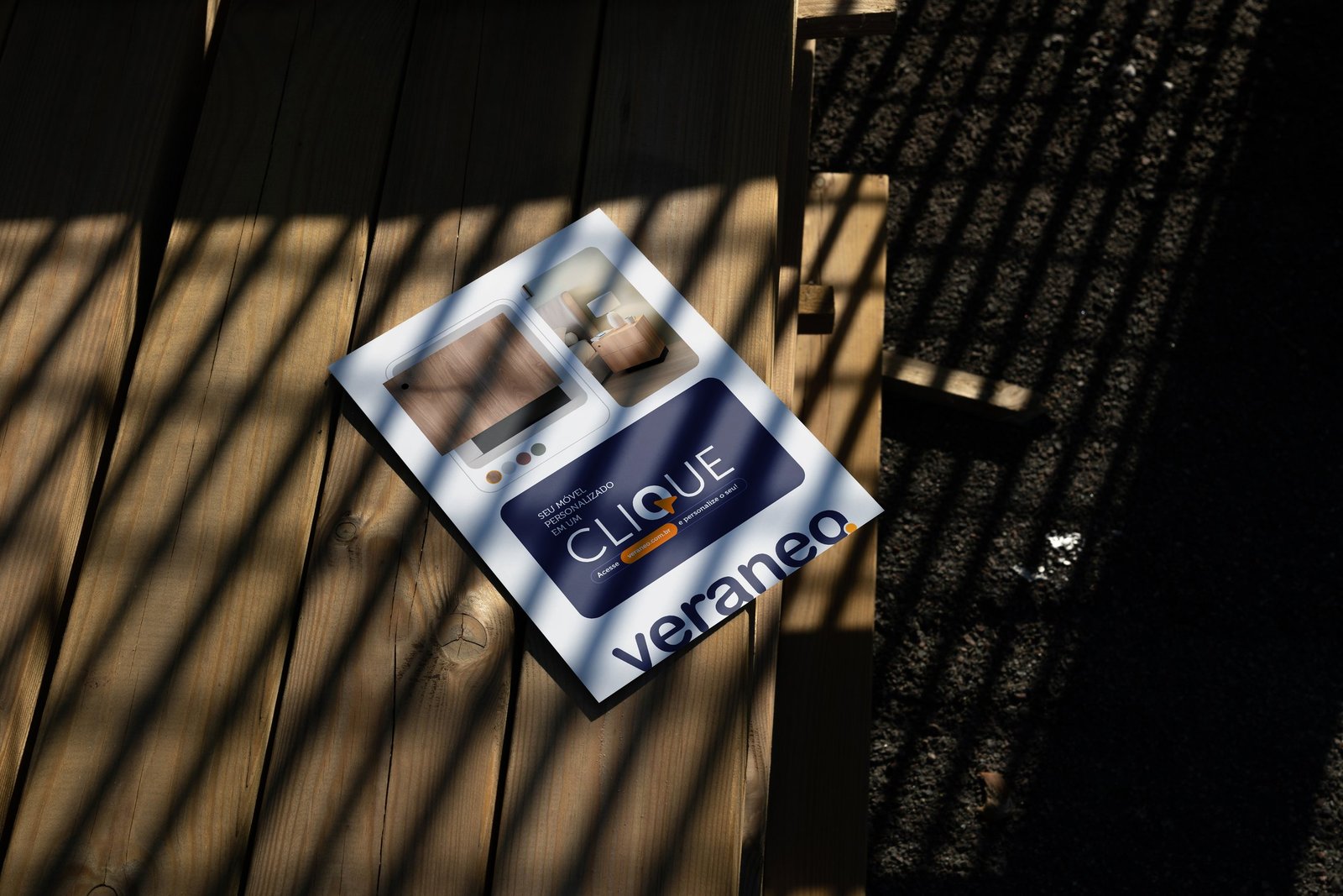 Papelaria da marca sobre madeira ripada, atravessada por luz e sombra.